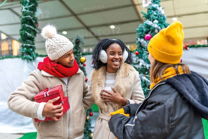 Happy friends exchanging gifts and enjoying christmas time together at a decorated christmas market