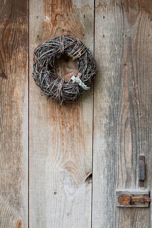 Door wreath made of natural materials in front of an old wooden door, North Rhine-Westphalia, Germany