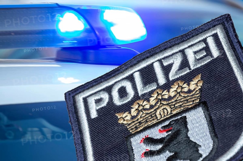 (Photomontage) Symbolic image of a police operation in Berlin: Berlin police emblem in front of flashing blue lights