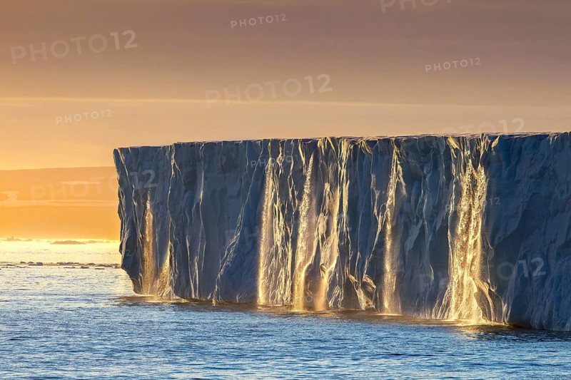 Waterfalls at edge of the Brasvellbreen glacier from ice cap Austfonna debouching into Barents Sea at sunset, Nordaustlandet, Svalbard, Spitsbergen