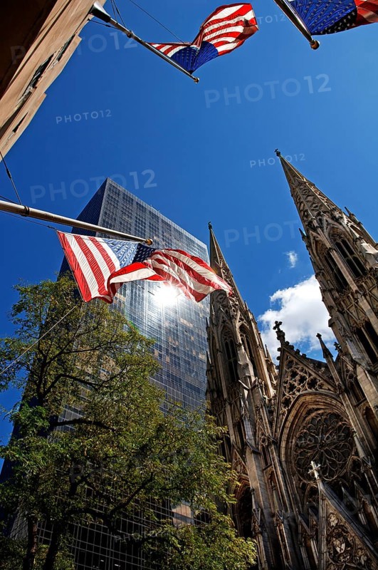 Towers of St Patrick's Cathedral in front of skyscrapers, waving US flags, New York City, USA