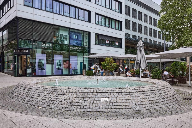 Cobblestone fountain, fountain, water, pedestrian zone, general architecture, shop window, outdoor area of a restaurant, sunshades, perfumery, facades, windows, cloudy, diffuse light, intersection Kronprinzstraße with Büchsenstraße, Stuttgart, state capital, Stuttgart city district, Baden-Württemberg, Germany