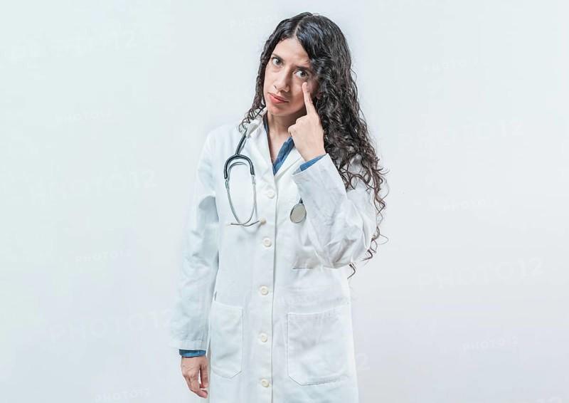 Suspicious female doctor looking you isolated. Suspicious young doctor pointing at eye, isolated