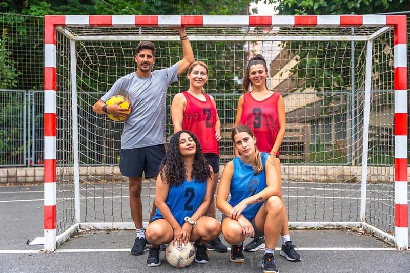 Five a side soccer team posing confidently with soccer balls in front of the goal, embodying teamwork and sportsmanship while preparing for a friendly match on the field