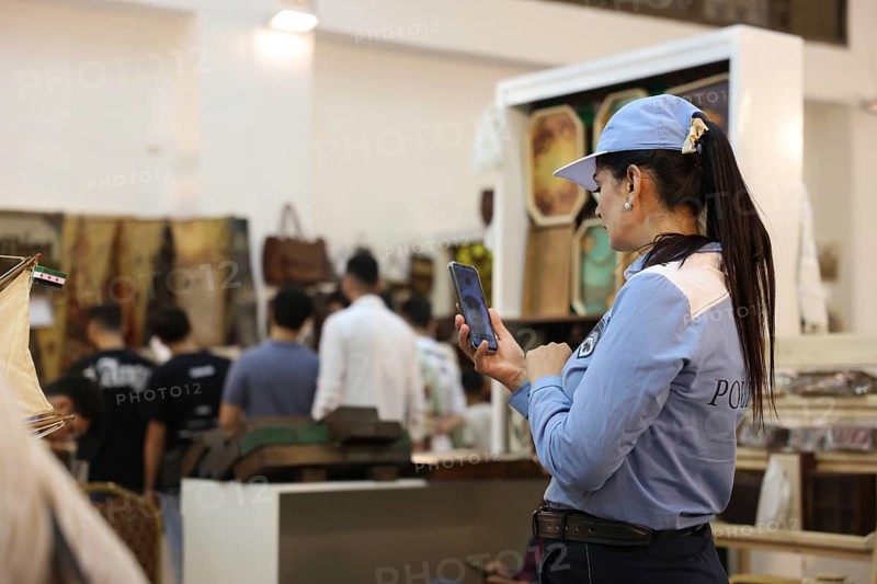 A female member of Syria's newly established tourist police stands inside the Damascus International Fair wearing a blue uniform. The tourist police force was formed after the fall of Assad's regime and deployed at the exhibition to interact with visitors and provide security services, Damascus, Damascus, Syria