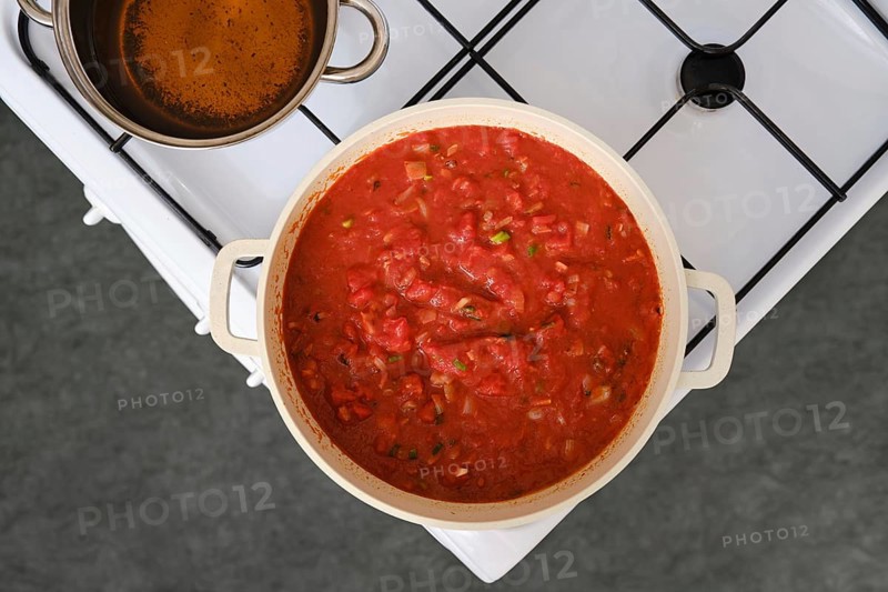 Overhead view of cooking tomato and bread soup on a stove
