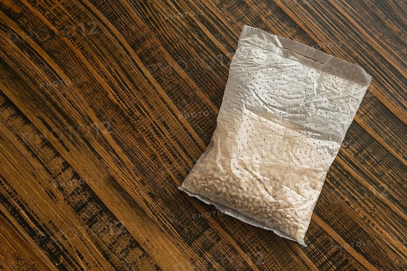 A sachet containing pearl barley is placed on a wooden kitchen table. It is ready for cooking, showcasing the natural beauty of this versatile grain typically used in healthy meals