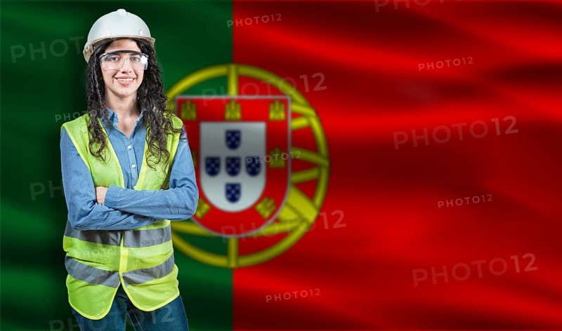 Portrait of smiling female engineer with Portuguese flag in background. Young female construction engineer with Portugal flag