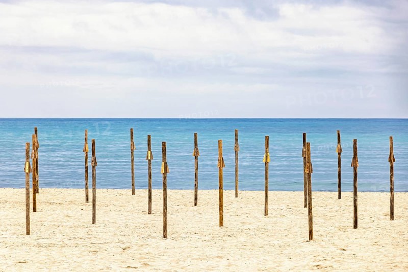 Parasol poles on a empty sandy beach by the Mediterranean sea with a seascape view to the horizon, Mallorca, Spain