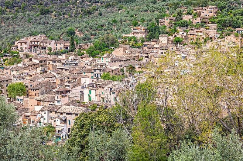View at an old idyllic village on a mountainside with houses and lush green trees, Sóller, Mallorca, Spain