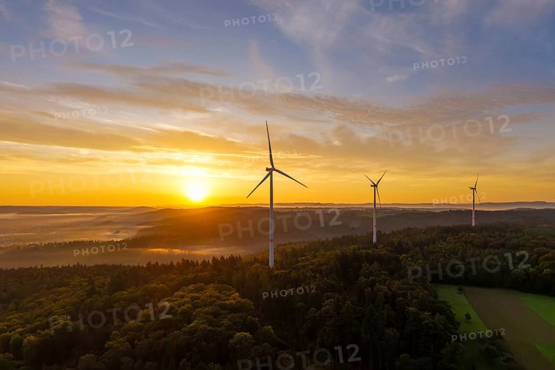 Three wind turbines at sunrise with a golden sky over a forest landscape, near Schorndorf, Rems-Murr district, Rems-Murr-Kreis, Baden-Württemberg, Germany
