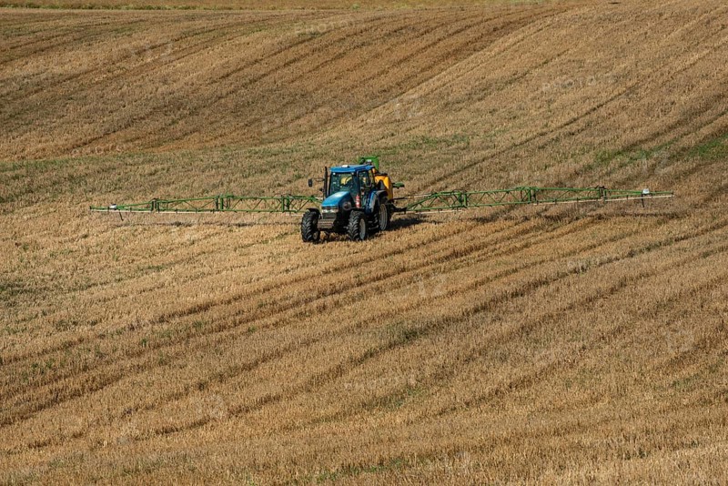Tractor spreading fertilizer on harvested stubble field in Ystad municipality, Skåne county, Sweden, Scandinavia