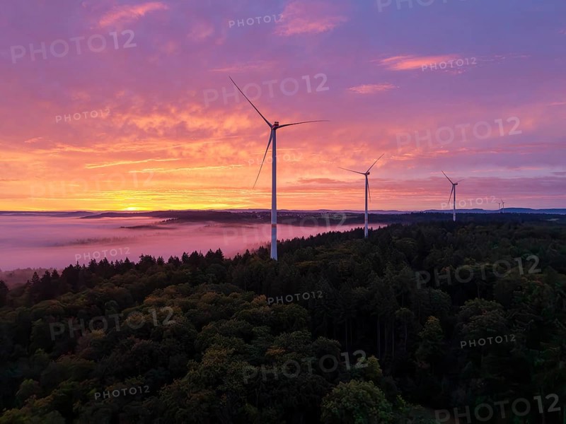 Several wind turbines above a forest in front of sunrise in the warm colours of dusk, near Schorndorf, Rems-Murr district, Rems-Murr-Kreis, Baden-Württemberg, Germany