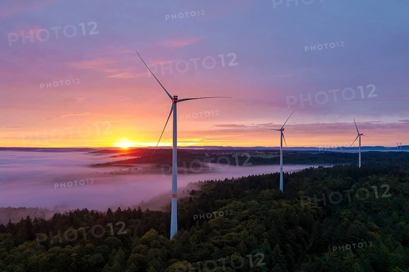 Wind turbines stand high above a misty forest illuminated by an impressive sunrise, near Schorndorf, Remstal, Rems-Murr-Kreis, Baden-Württemberg, Germany