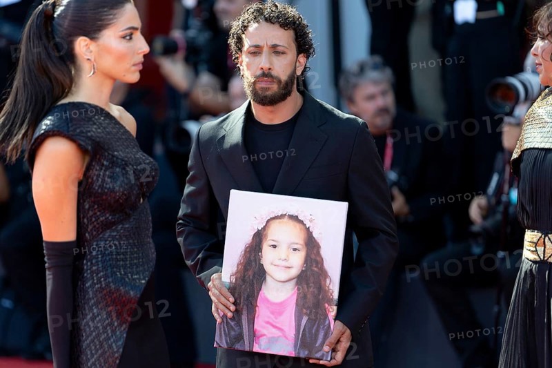 Venice, Italy - 3 September 2025: Kaouther Ben Hania (R) and Saja Kilani (L) and Motaz Malhees (C) with a portrait of five-year-old Palestinian girl Hind Rajab, who was killed by the Israeli army in the Gaza Strip in January 2024, during the Red Carpet of - The Voice Of Hind Rajab - during the 82nd Venice International Film Festival