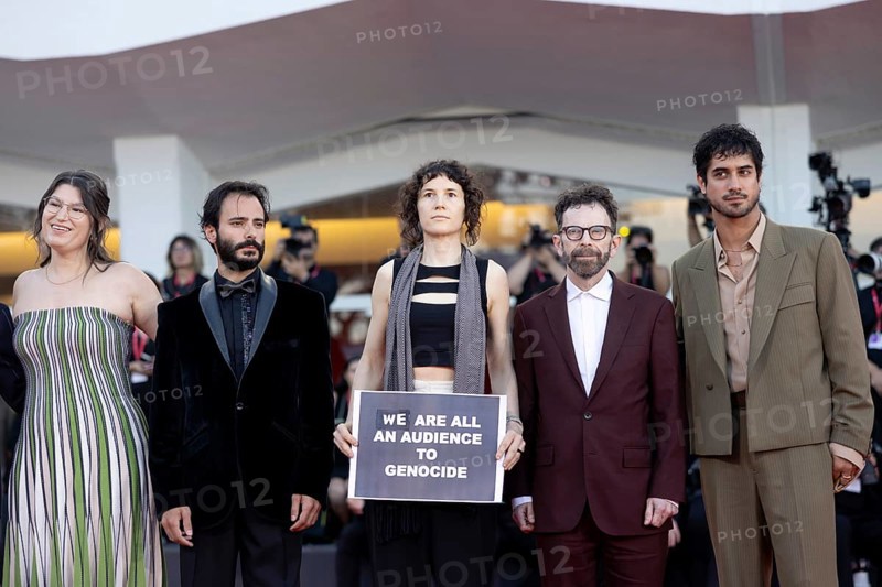 Venice, Italy - 1 September 2025: Charlie Kaufman, Eva H.D., Josef Akiki, Emily McCann Lesser, Avan Jogia and Isabelle Deluce with a sign reading - We are all an audience to Genocide - during the red carpet of - The Smashing Machine - during the 82nd Venice International Film Festival