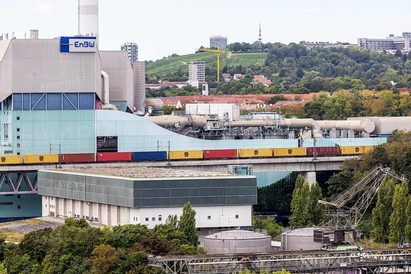 Goods train travelling on the Schusterbahn, Münster viaduct with EnBW Energie Baden-Württemberg combined heat and power plant. Stuttgart, Baden-Württemberg, Germany