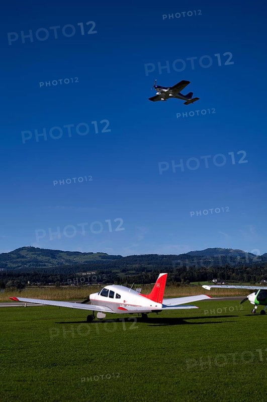 BRM Aero Bristell B23 identification aircraft registration HB-KGU taking off over Piper Archer II HB-PPY on the ground, Wangen-Lachen airfield, LSPV, Canton Schwyz, Switzerland