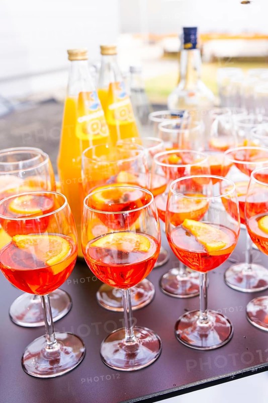 Several cocktail glasses with orange-coloured drink and orange slices, arranged on a table outdoors, Lake Constance, Germany