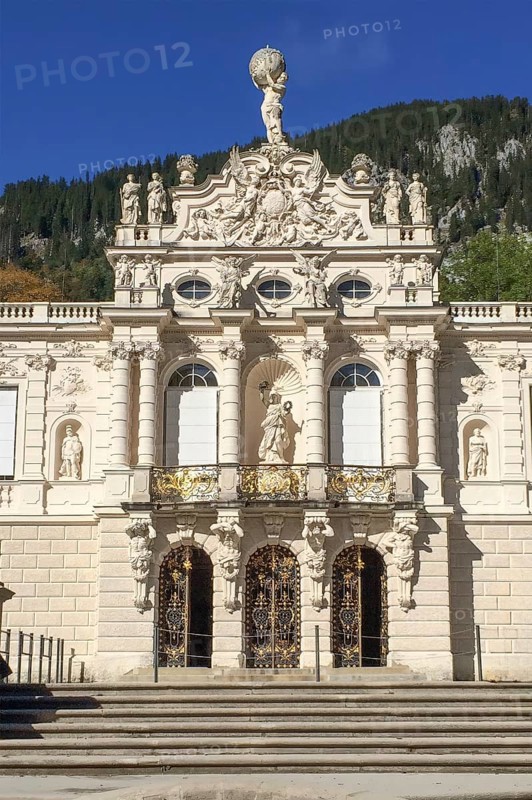 View of portal and façade entrance to Linderhof Palace in the Neurococo style with sculptures made of limestone and cast zinc, at the top of the pediment of the main façade coat of arms of the Kingdom of Bavaria, above it statue of Atlas with celestial globe, Ettal, Bavaria, Germany