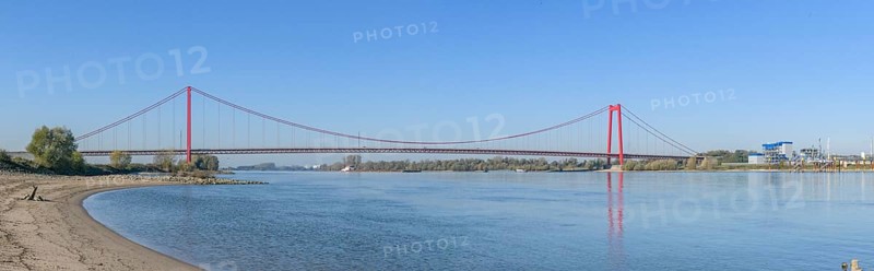 Panorama view from the left bank of the Rhine, western bank of the Rhine, of an earth-anchored suspension bridge with two abutments and red steel piers nicknamed the Golden Gate of the Lower Rhine over the River Rhine, with a total length of 1228 metres the longest suspension bridge in Germany, Emmerich, North Rhine-Westphalia, Germany