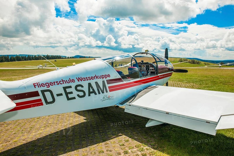 View of Robin Aircraft, DR 400-180R Remo light aircraft single-engine cantilever low-wing monoplane in wooden construction from Fliegerschule Wasserkuppe suitable as tow plane for gliders stands with open cockpit canopy in parking position on apron, Wasserkuppe airfield, Rhön, Gersfeld, district of Fulda, Hesse, Germany