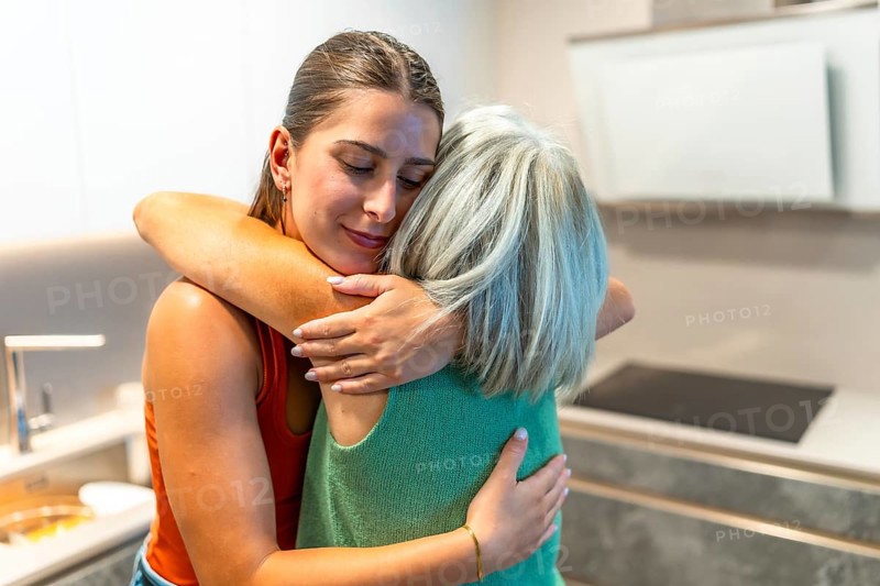 Daughter embracing senior mother, sharing a heartfelt moment of love and support in the comfort of their cozy kitchen at home