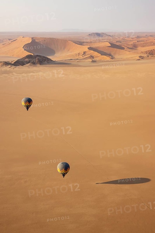 Two hot-air balloons above an arid plain at the edge of the Namib Desert. Aerial view from another balloon. Namibia