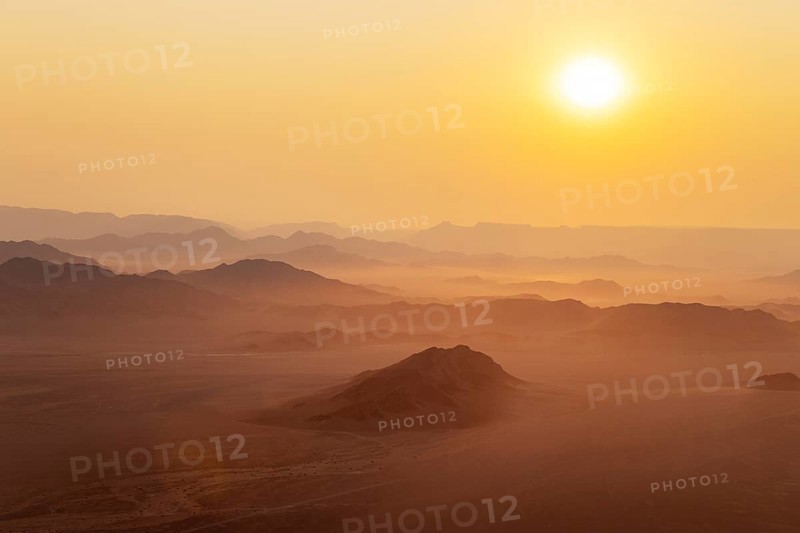 Arid plains and isolated mountain ridges at the edge of the Namib Desert. At sunrise. Aerial view from a hot-air balloon. Kulala Wilderness Reserve, Namibia
