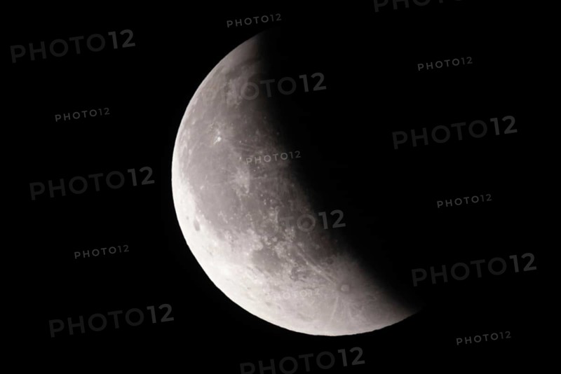 After a total lunar eclipse, the moon appears shortly after its rise in the evening sky as a so-called blood moon in front of it then begins to emerge from the Earth's umbra, Frankfurt am Main, Hesse, Germany