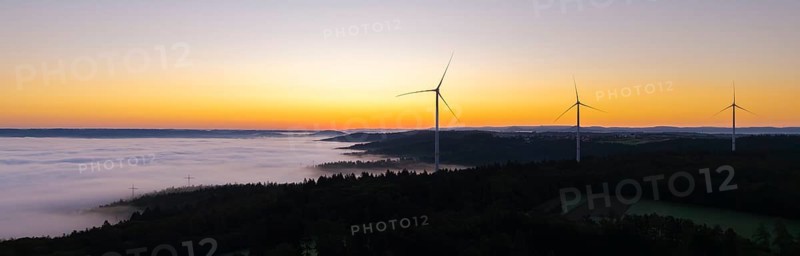 Row of wind turbines along the horizon at sunrise with fog in the distance, near Schorndorf, Remstal, Rems-Murr-Kreis, Baden-Württemberg, Germany