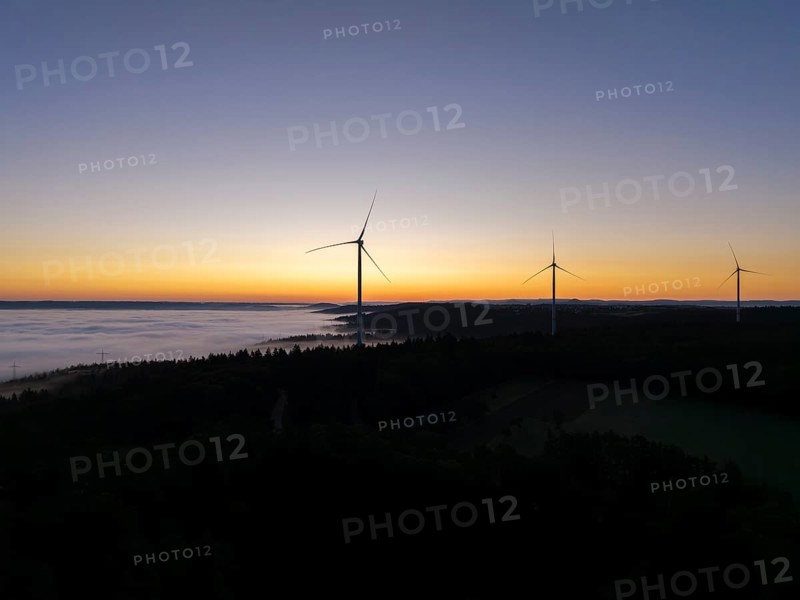 Three wind turbines in front of an orange and blue sky at sunrise with fog, near Schorndorf, Remstal, Rems-Murr-Kreis, Baden-Württemberg, Germany