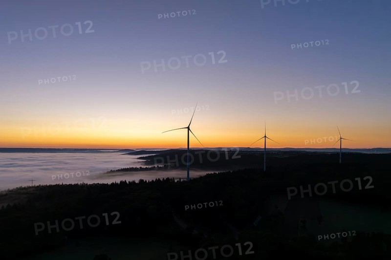 Wind turbines in front of a bright blue and orange sky at sunrise with fog over the landscape, near Schorndorf, Rems-Murr district, Rems-Murr-Kreis, Baden-Württemberg, Germany