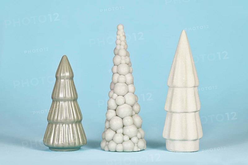 Three different shaped light green ceramic Christmas trees on blue background