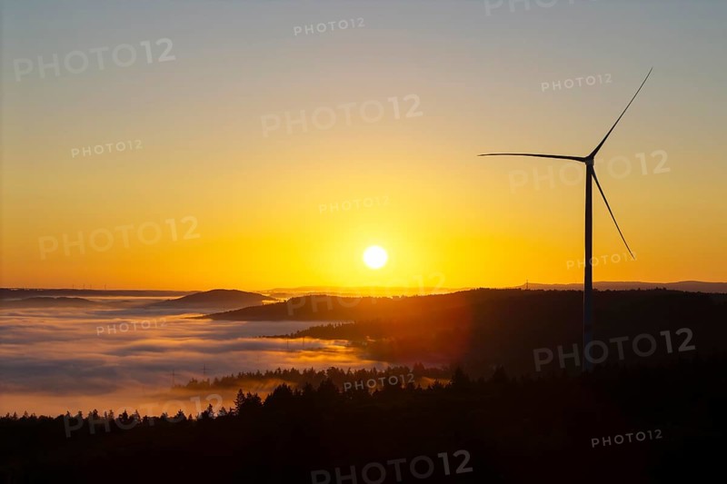 A wind turbine rises into the sunrise sky above misty hills, near Schorndorf, Rems-Murr district, Rems-Murr-Kreis, Baden-Württemberg, Germany