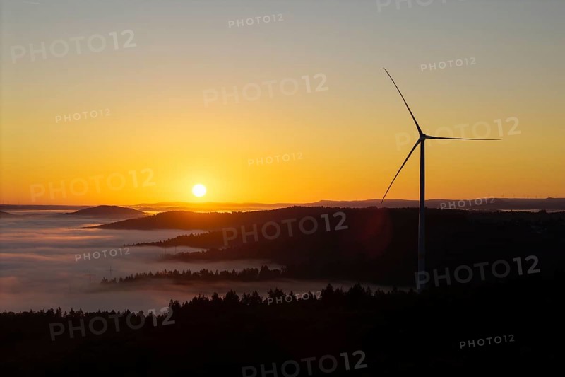 A wind turbine stands over the hills in front of sunrise, near Schorndorf, Rems-Murr district, Rems-Murr-Kreis, Baden-Württemberg, Germany