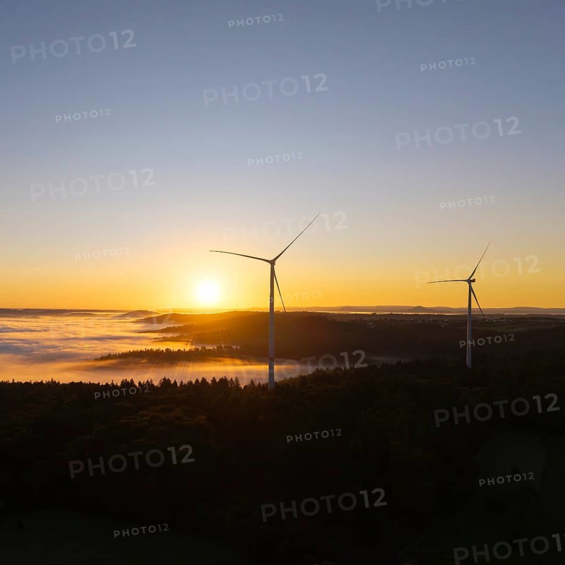 Two wind turbines overlook the foggy forest landscape at sunrise, near Schorndorf, Rems-Murr district, Rems-Murr-Kreis, Baden-Württemberg, Germany