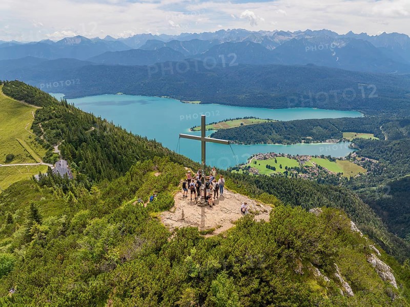 Group of people on a mountain top with a view of a lake and surrounding mountains, Herzogstand summit, Walchensee, Schlehdorf, Germany