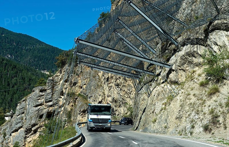 Motor vehicles travelling under safety nets on the rockfall-prone road Les Pontis, Val d'Anniviers, Valais, Switzerland