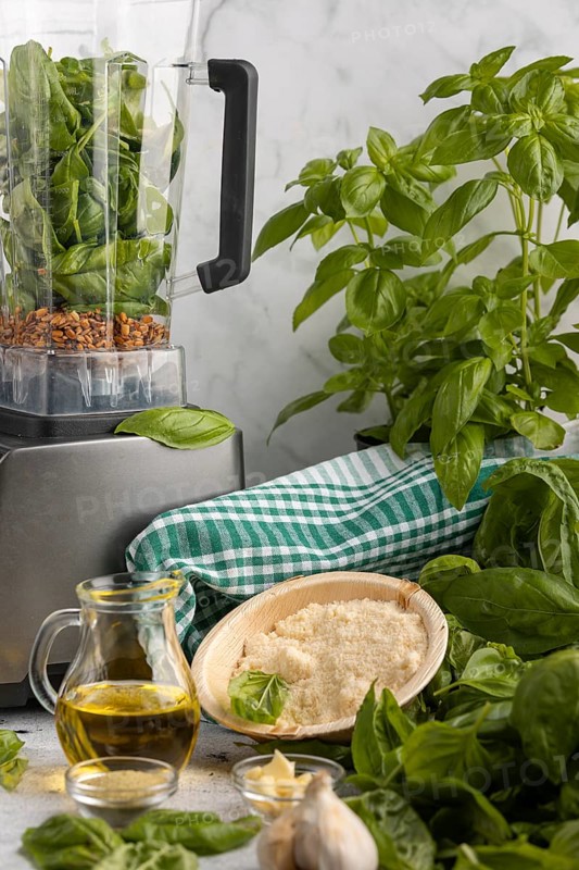Blender with basil and sunflower seeds alongside other ingredients for pesto