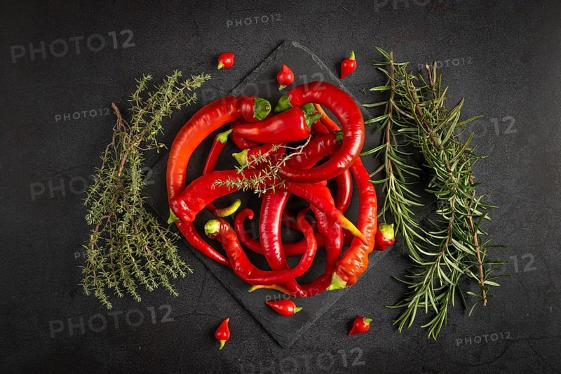 Hot red peppers and herbs, rosemary and thyme, on a dark background