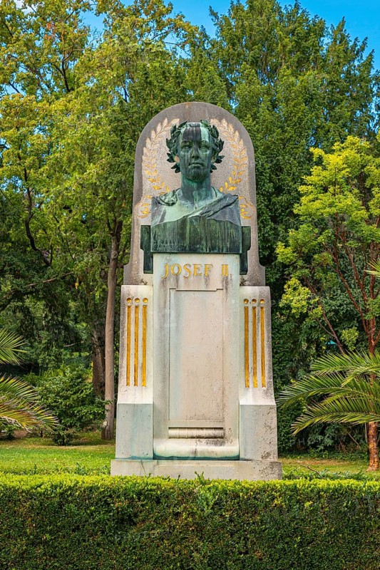 Bust of Joseph II on a monument, embedded in lush greenery and trees, spa garden Baden, Lower Austria, Austria