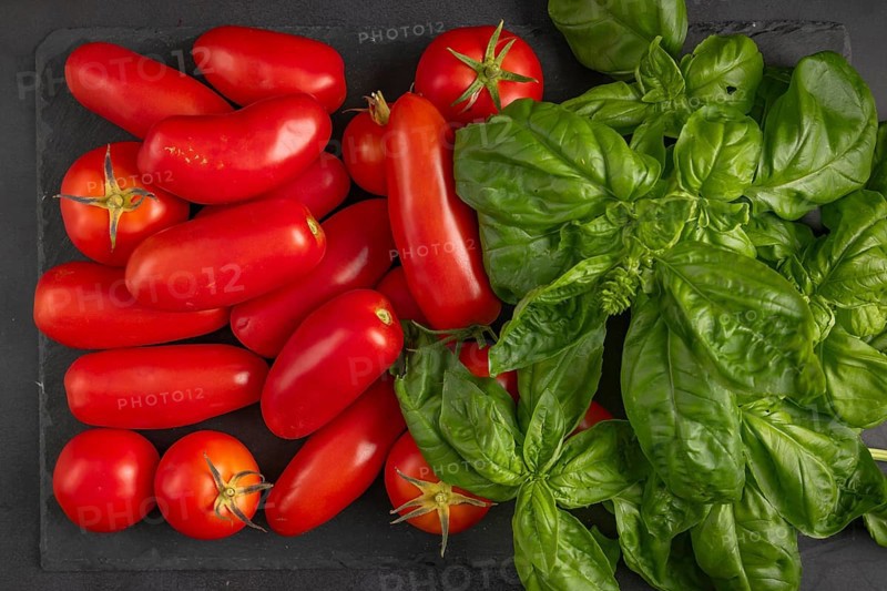 Various tomatoes and fresh basil on a slate plate