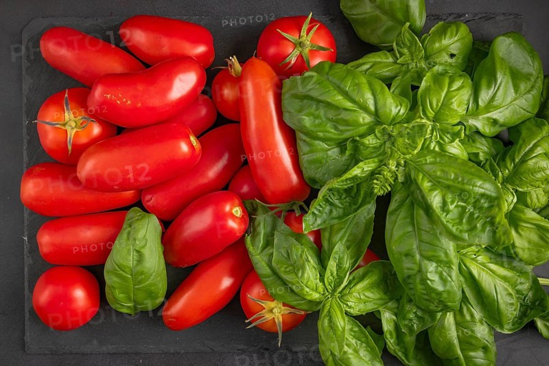 Fresh tomatoes and basil arranged on a dark slate plate