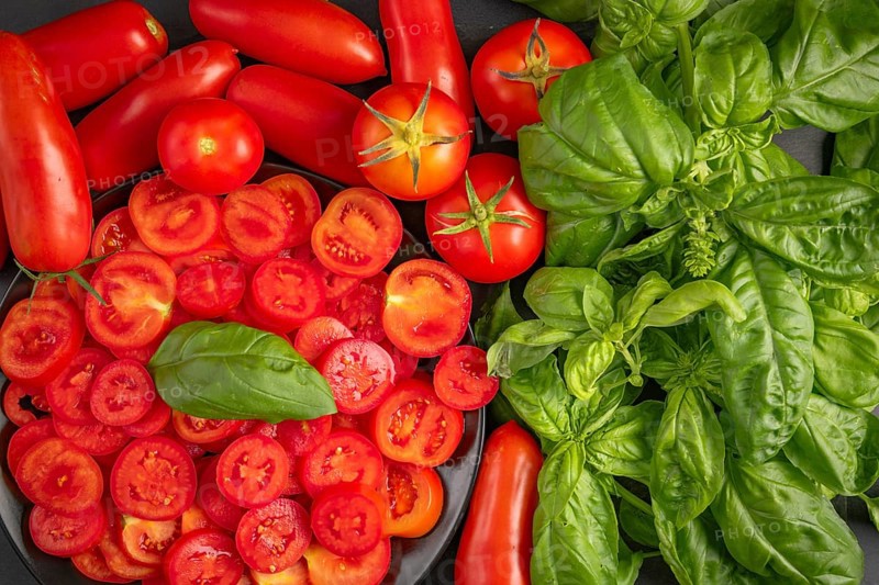 Sliced and whole tomatoes with fresh basil, colourfully presented