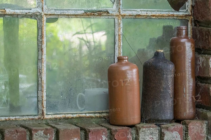 Three old earthenware bottles in front of a stable window, North Rhine-Westphalia, Germany