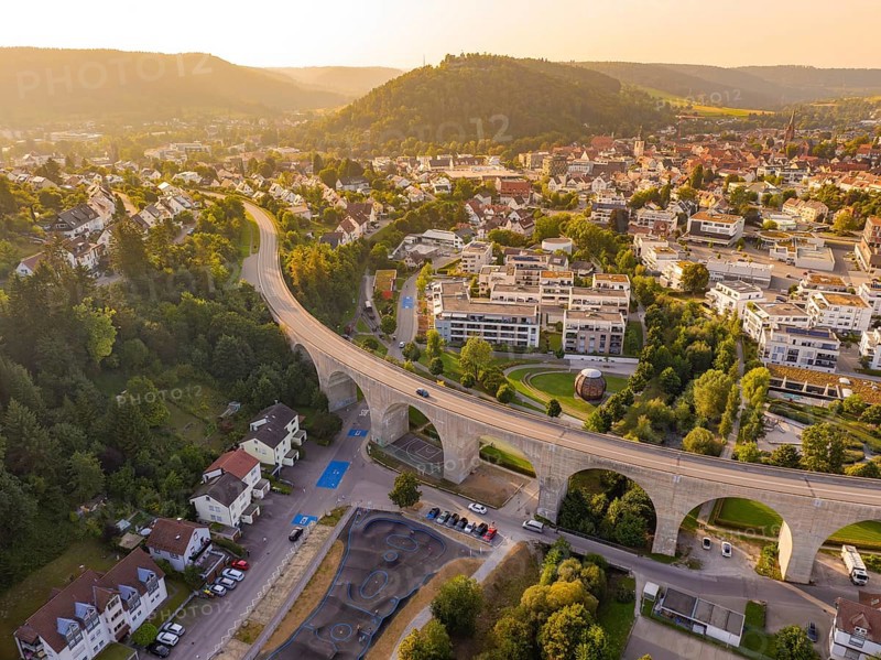 Aerial view of a town with viaduct and surrounding hills in warm sunlight, small town Perle Nagold, Black Forest, Germany