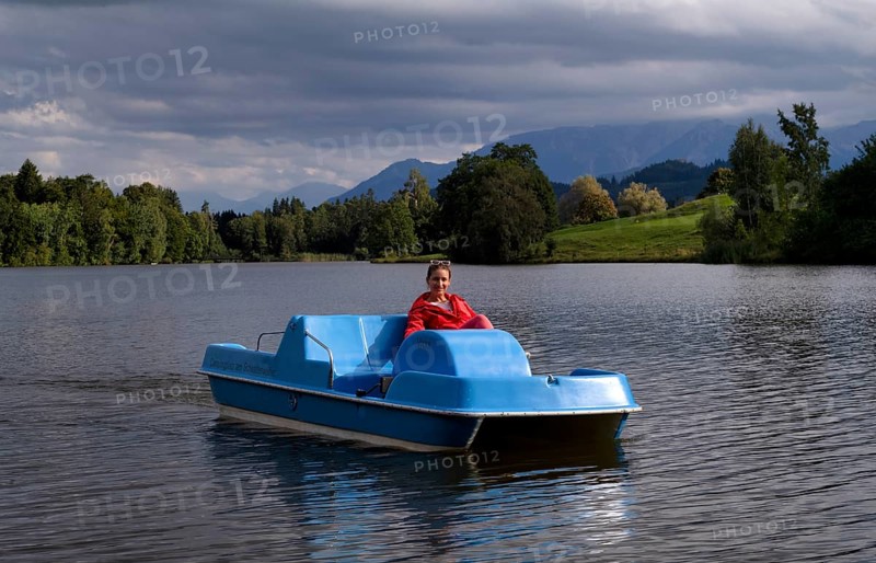 Woman, blonde, red jacket, riding pedal boat, bathing lake, lake, Schwaltenweiher near Seeg, Allgäu Alps, East Allgäu, Allgäu, Swabia, Bavaria, Germany