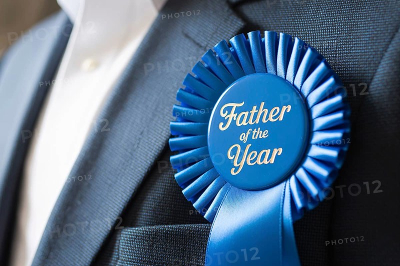 Close up of Father of the Year award ribbon pinned to man's suit chest. Celebration of fatherhood and recognition. Generative AI, AI generated