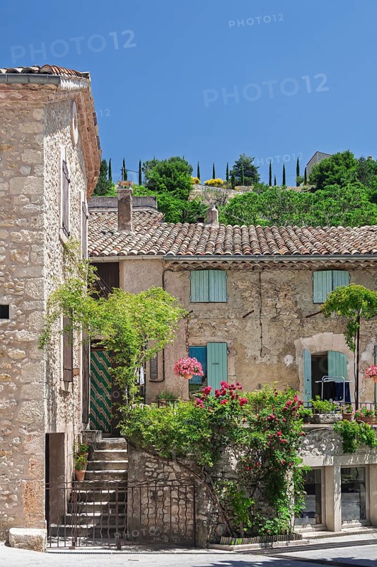 A rustic house with a terrace decorated with flowers, shutters and green hills in the background, Aurel, Département Vaucluse, Region Provence-Alpes-Côte d'Azur, South of France, France